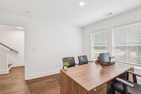A home office with a large desk and office chairs.