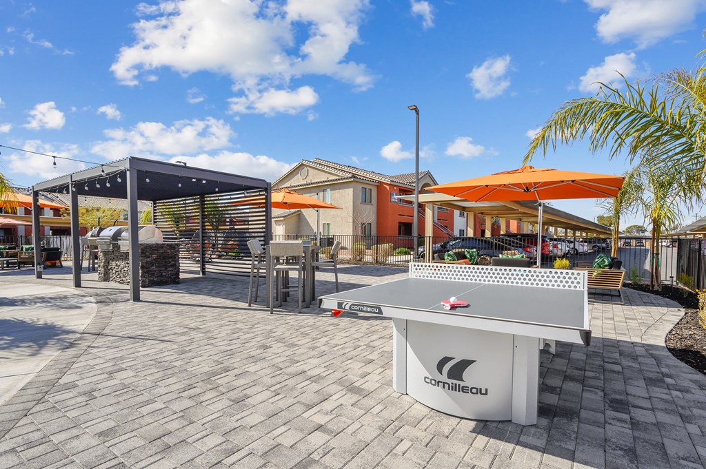 A white table tennis table with the brand name "Camilleau" on it is placed on a patio.