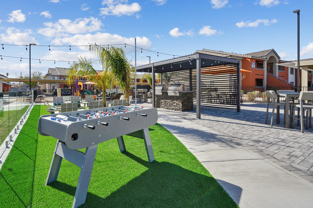 A foosball table is in the middle of a grassy area.