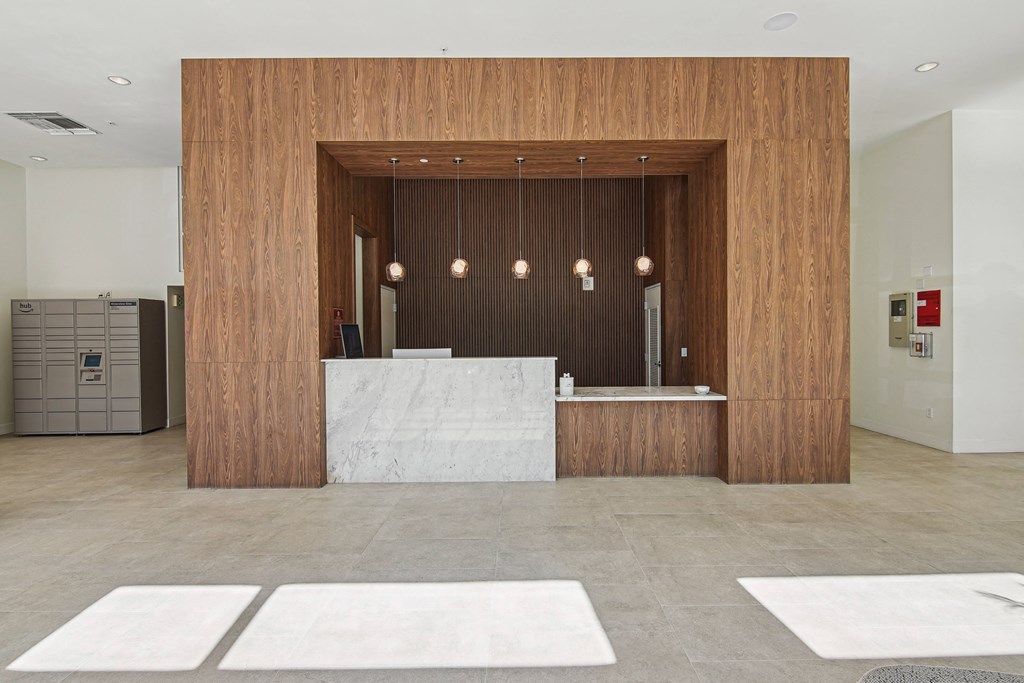 1- & 2-Bedroom Apartments for Rent in Miami, FL – Riverview One Apartments – A reception area with a white counter and a wooden wall.