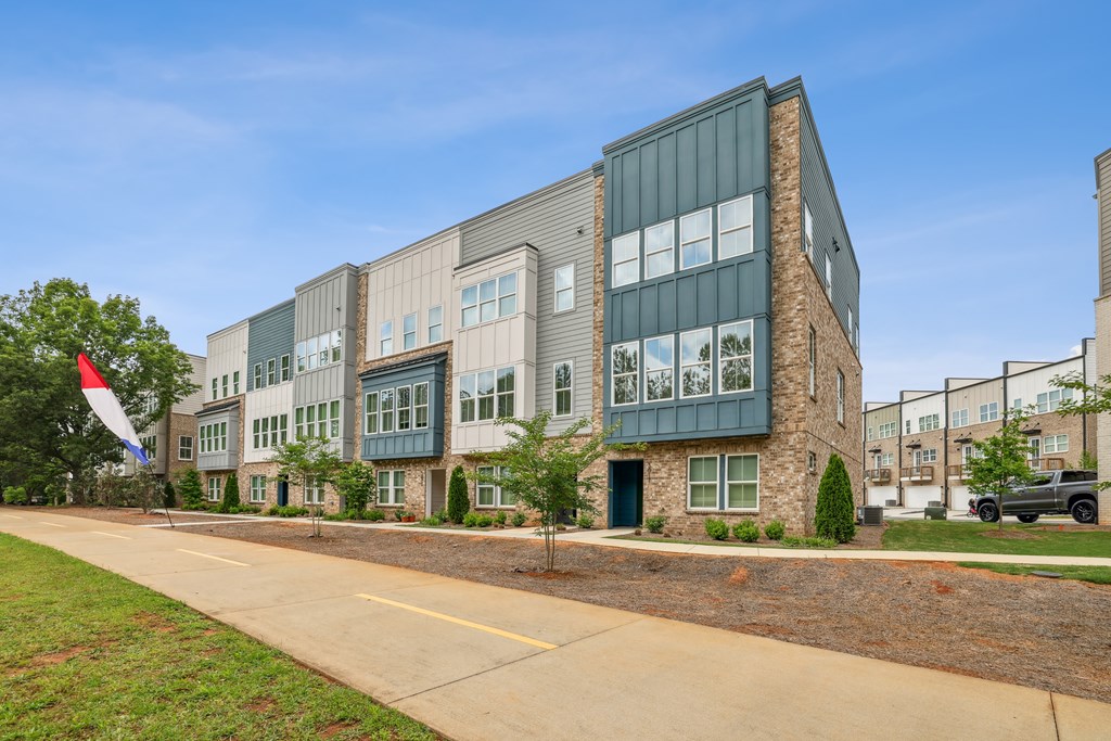 Exterior view of townhome buildings with landscaped grounds at Henley Avondale in Avondale Estates, GA, a pet-friendly community.