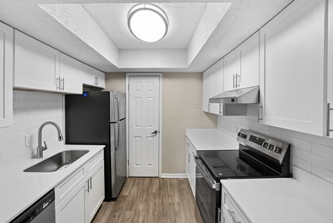 A small, white kitchen with a black fridge and stove.