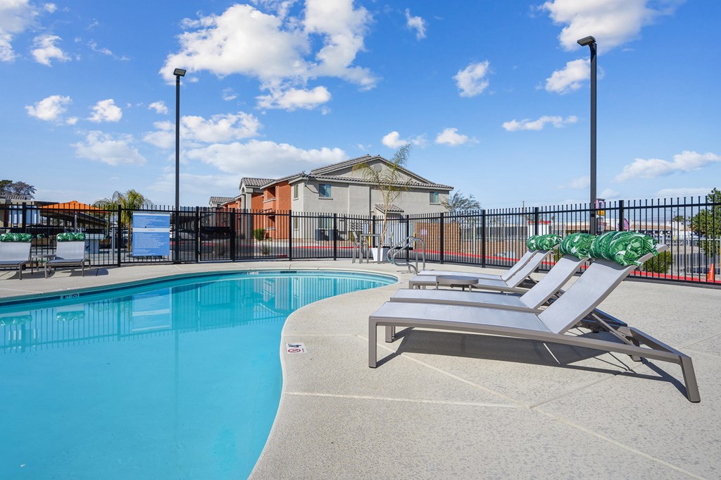 A pool with a sun lounger and a building in the background.