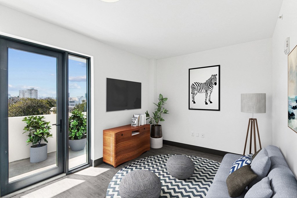 Pet-Friendly Apartments in South Beach Miami – The Anamar at Collins Park – A living room with a grey sofa, a wooden side table, and a zebra print rug.