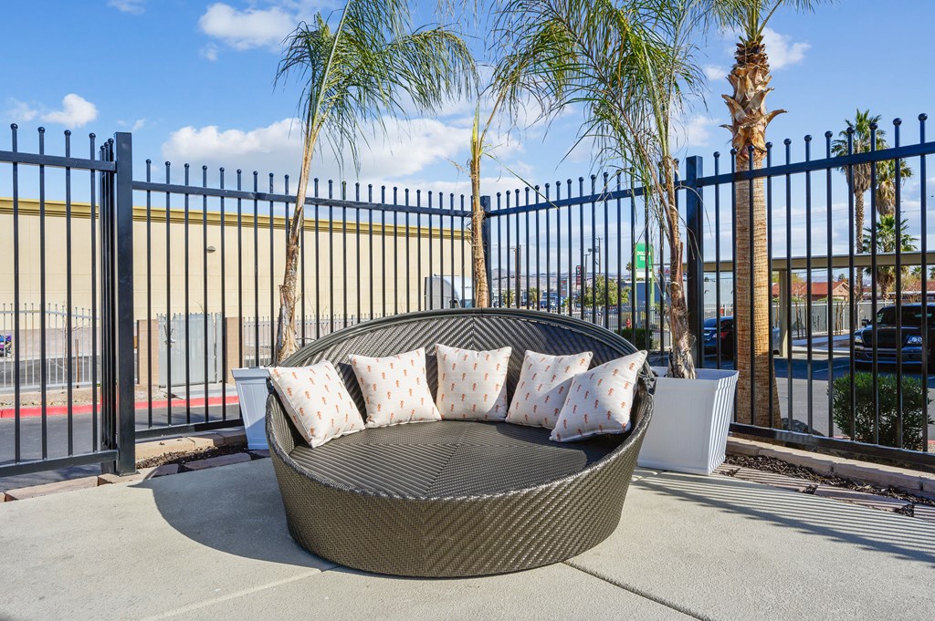 A black metal fence surrounds a circular wicker sofa.