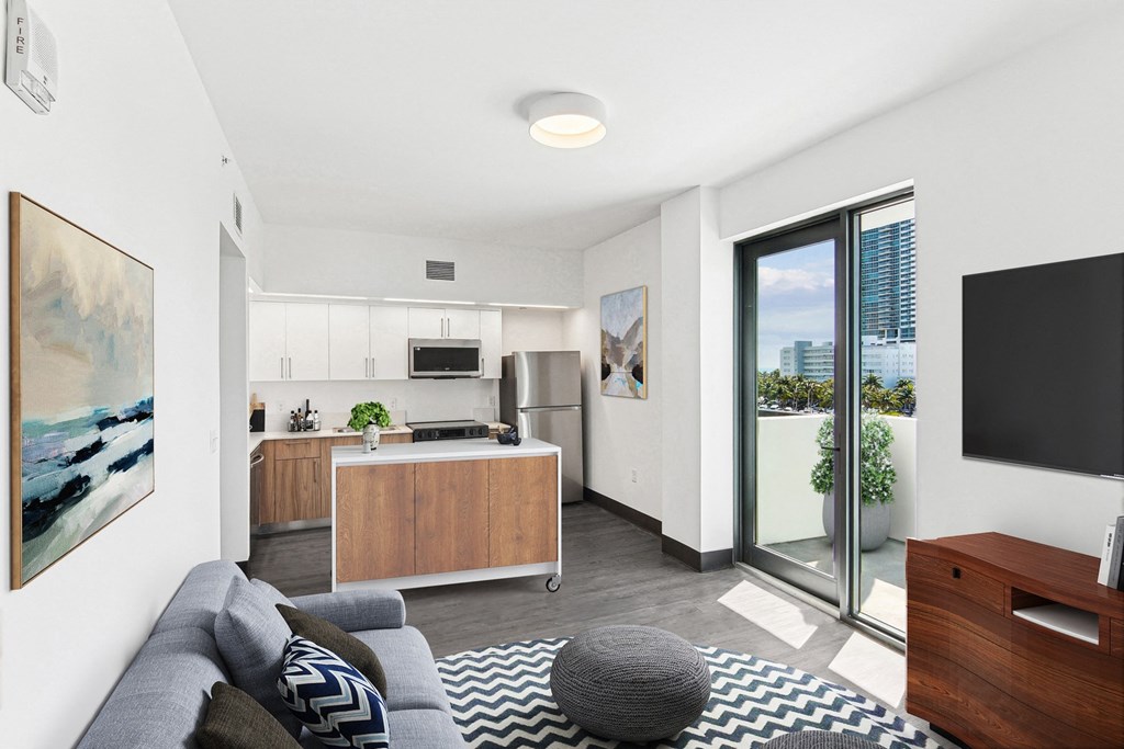 Downtown Miami, FL Apartments – The Anamar at Collins Park – A modern living room with a grey sofa and a grey pouf.