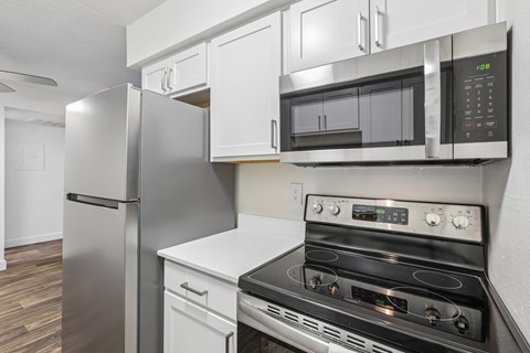 A modern kitchen with a stainless steel refrigerator, microwave, and oven.