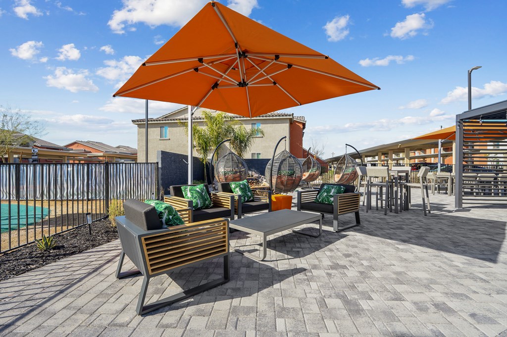A patio with a table and chairs under an orange umbrella.