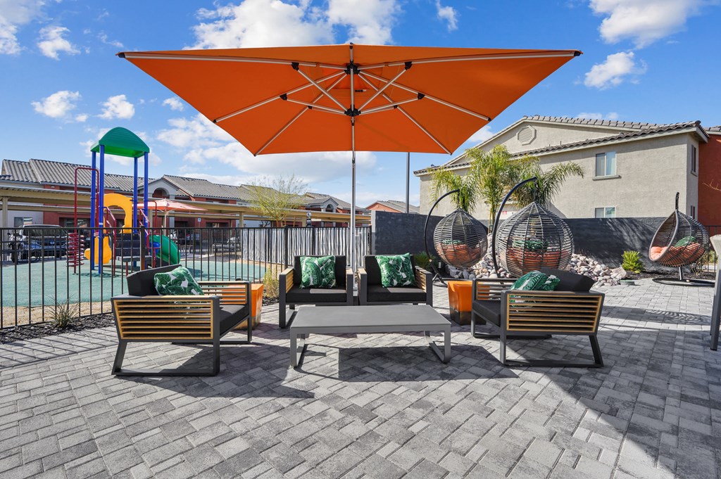 A patio with a large umbrella and a table with chairs.