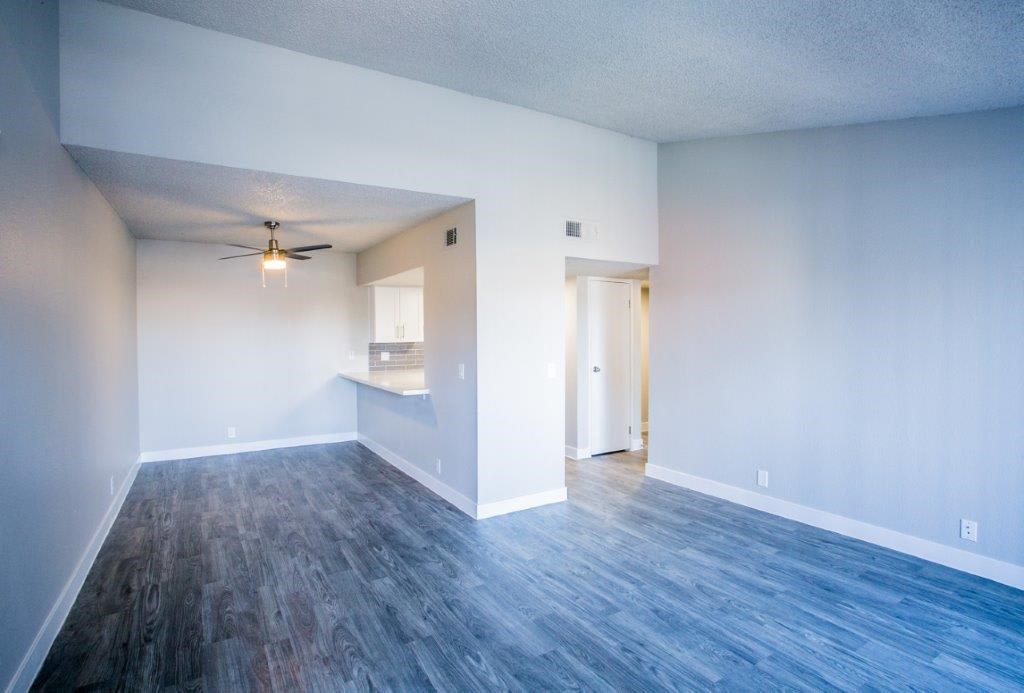 an empty living room with a ceiling fan