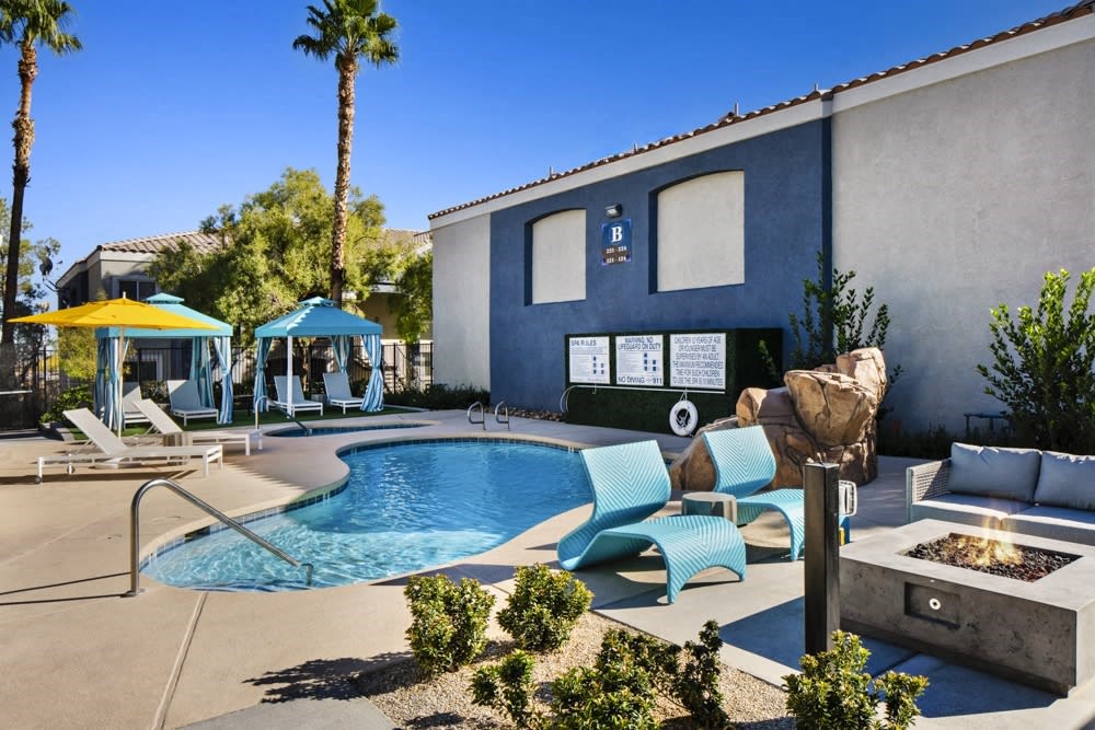a swimming pool with lounge chairs and a fire pit in front of a building