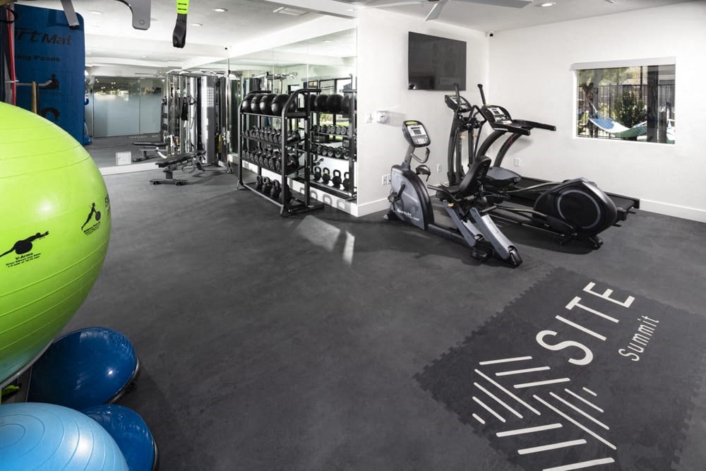 a gym with cardio equipment and weights on the floor