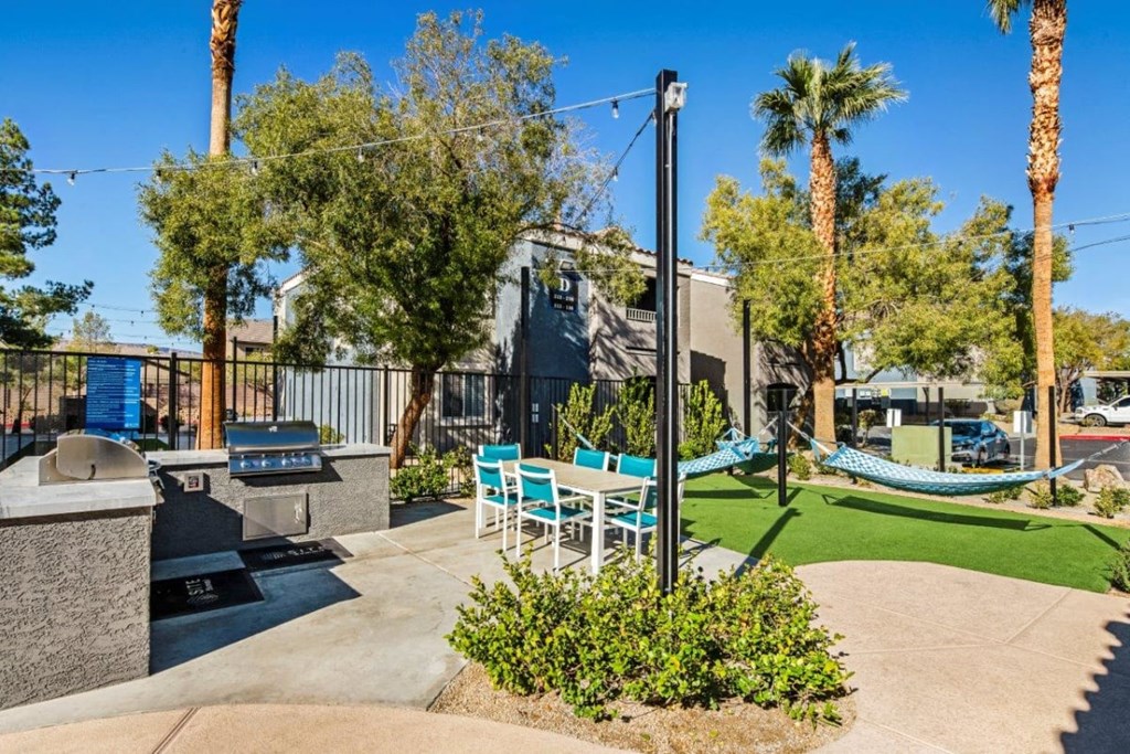a patio with chairs and a grill and a hammock in front of a building