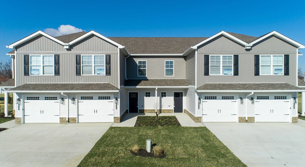 a house with white garage doors and a lawn