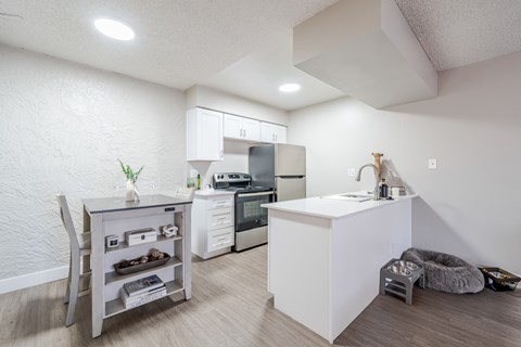 A kitchen with white appliances and a grey table.