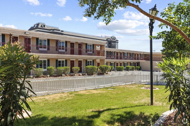 a building with a yard and a white fence in front of it