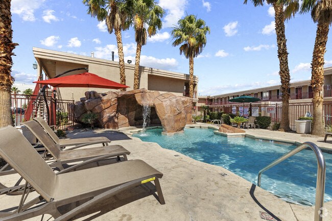 a resort style swimming pool with a waterfall and palm trees