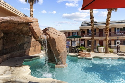 a resort style pool with a waterfall and rocks