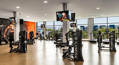 A gym with a variety of equipment including treadmills, weights, and exercise machines.