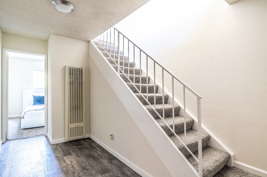 a white staircase in a house with a door to the right and a white couch in the