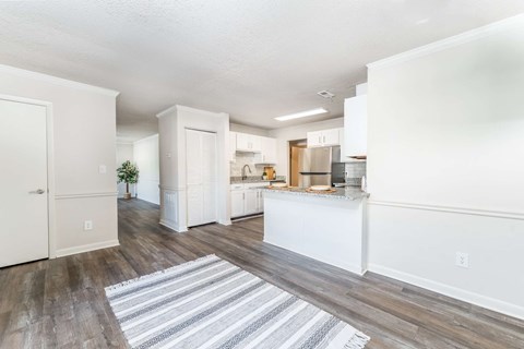 A kitchen with white cabinets and a striped rug on the floor.