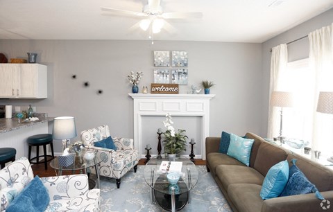 a living room with blue and white furniture and a white fireplace