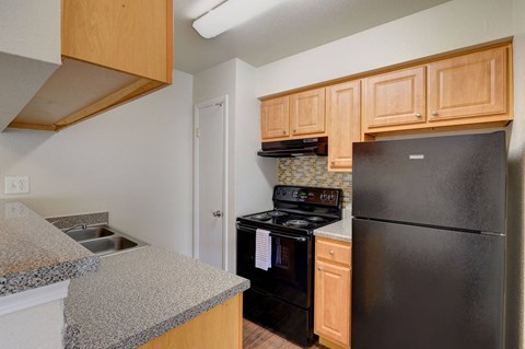 A kitchen with black appliances and wooden cabinets.