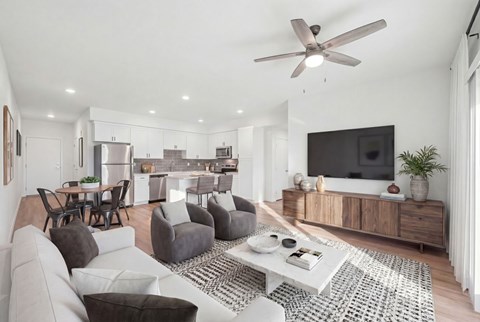 A modern living room with a grey sofa, a white coffee table, and a television on a wooden cabinet.