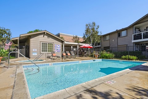 Community pool area with lounge chairs and mature landscaping at Sunnyside Senior Apartments in San Dimas, CA