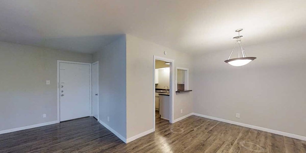 an empty living room with a door to a kitchen