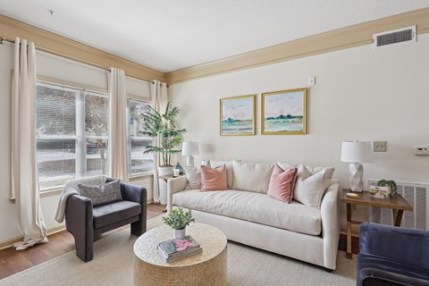 A living room with a couch, chair, and a table with a plant on it.