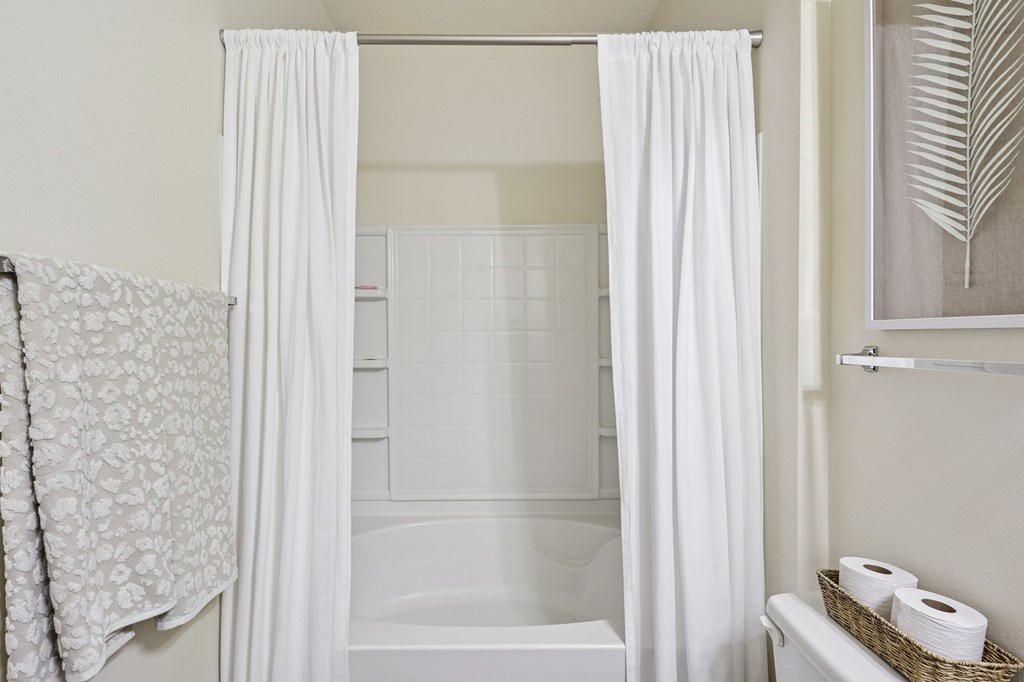 Clean full bathroom with white shower-tub combo and linen storage at Tattersall Village Apartments in Hinesville