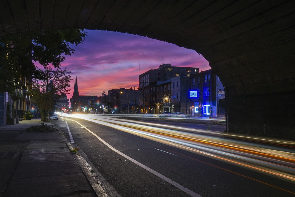 a purple and pink sky over a city street at night