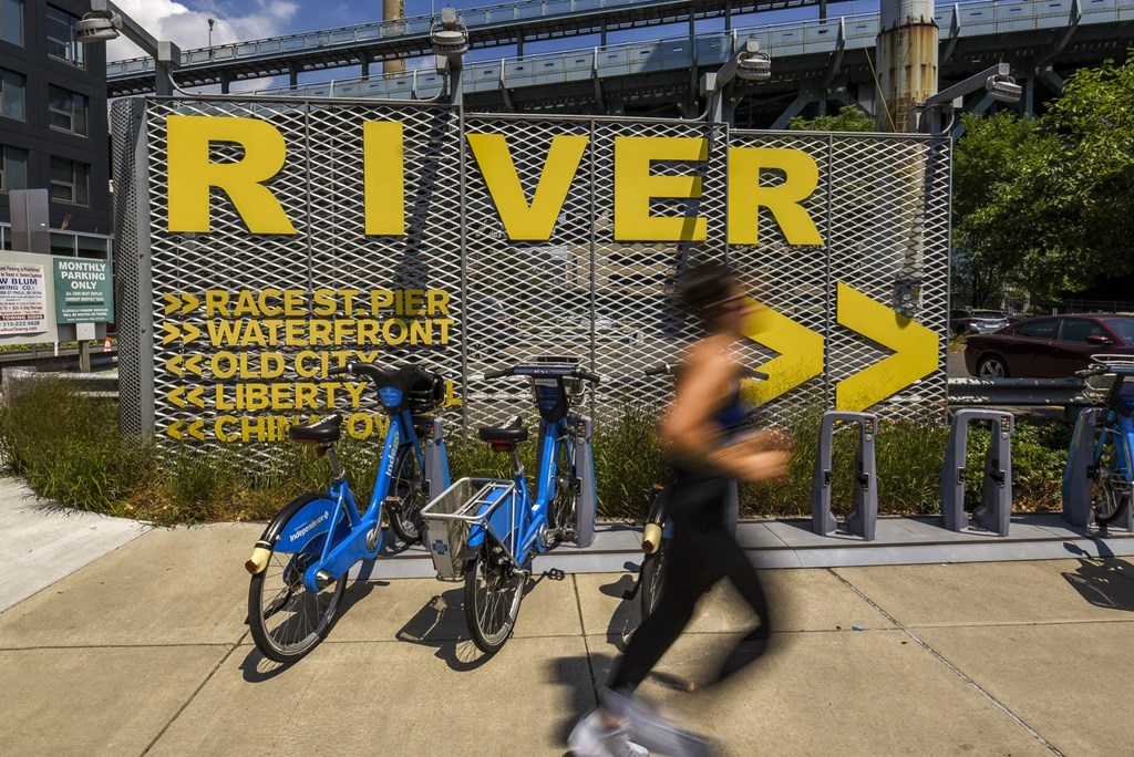 a woman walks past a sign that reads river