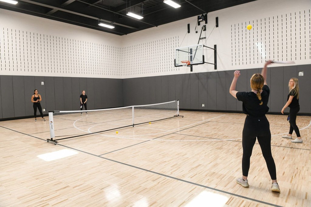 a group of people playing tennis in an indoor court