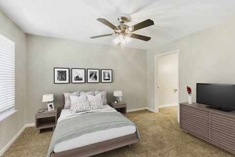 Bedroom with carpet, ceiling fan, and large windows letting in natural light at The Greens at Braelinn in Peachtree City, Georgia.