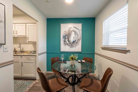 a dining room with a glass table and chairs and a kitchen