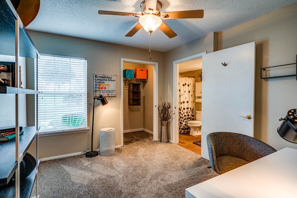 a bedroom with a ceiling fan and a desk with a chair