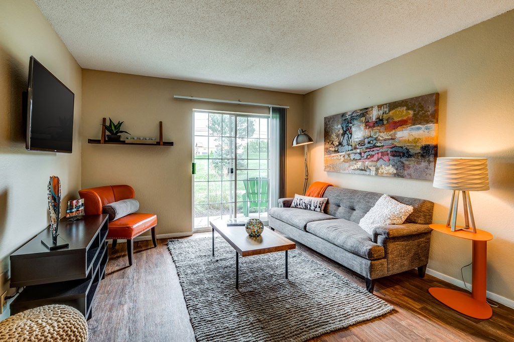 a living room with a couch and chair and a tv on the wall