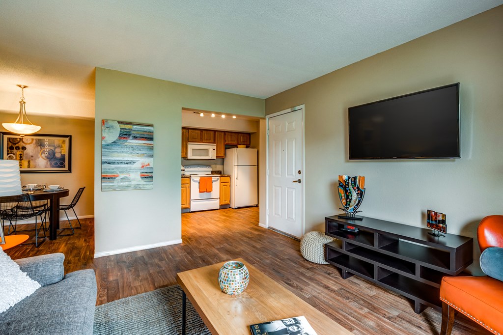 a living room with a tv and a kitchen in the background