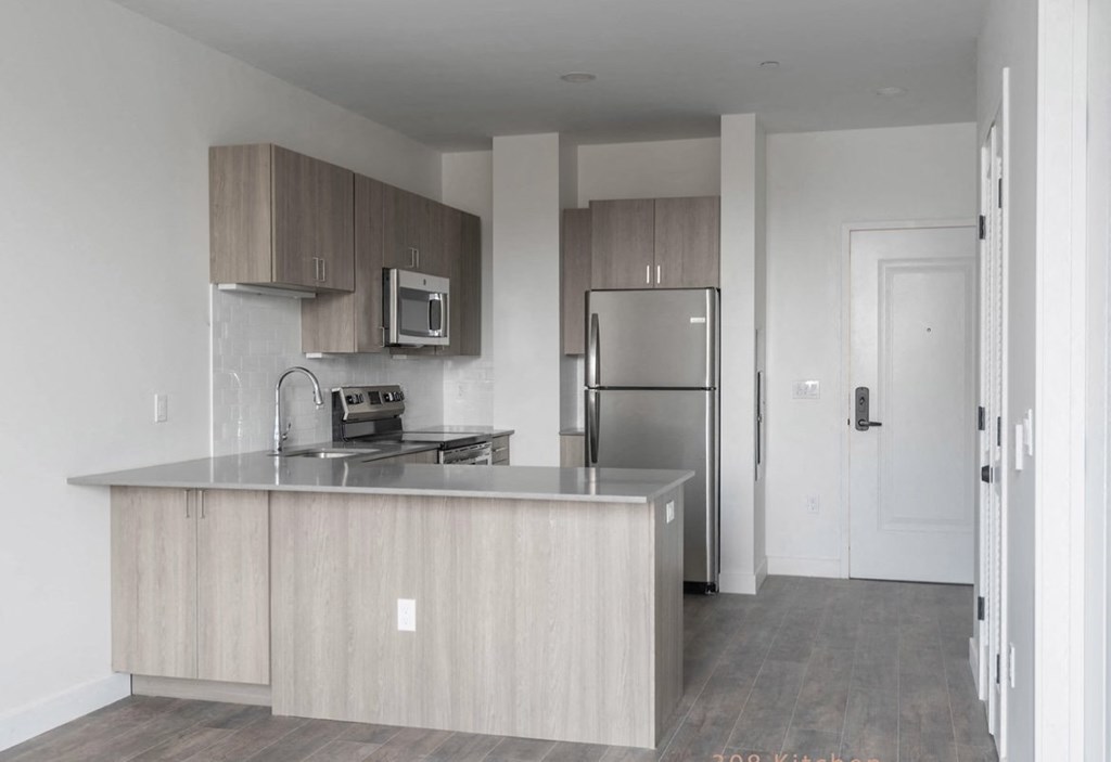 a kitchen with an island and stainless steel refrigerator