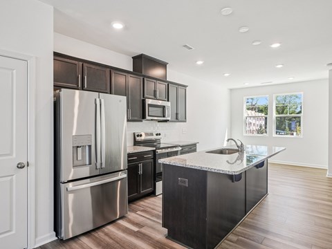 A modern kitchen with a stainless steel refrigerator and black cabinets.