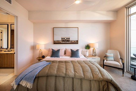 A bedroom with a large bed and a chair.