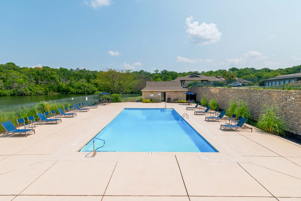 a swimming pool with blue chairs around it next to a river