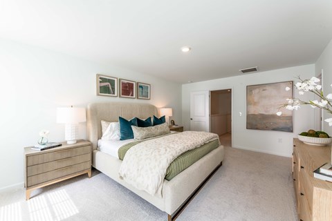 A bedroom with a large bed and a painting on the wall.