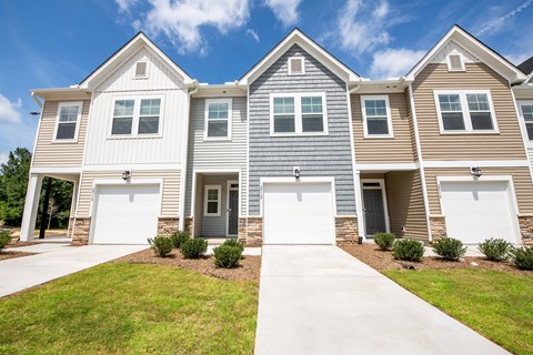 A row of houses with garages and front yards.