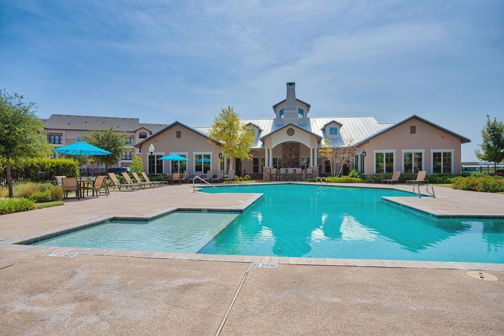 Apartment complex with large swimming pool and beach chairs