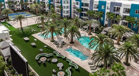 A large swimming pool surrounded by palm trees and lounge chairs.