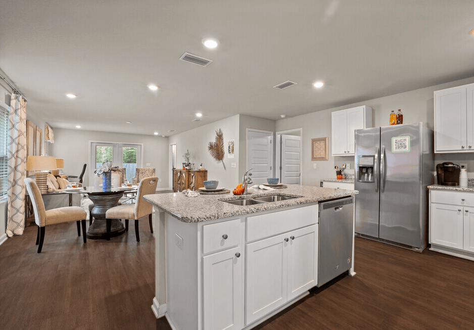 a white kitchen with a large island and a stainless steel refrigerator