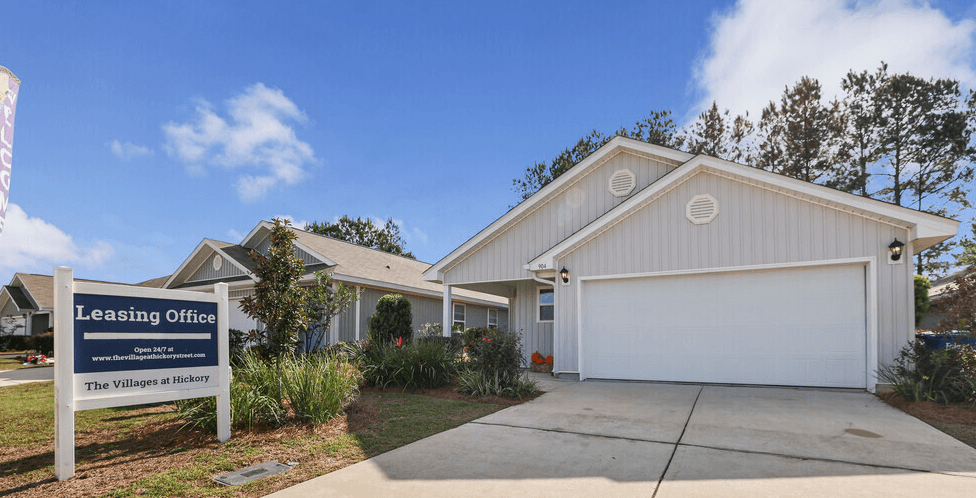 a white building with a leasing office sign in front of it